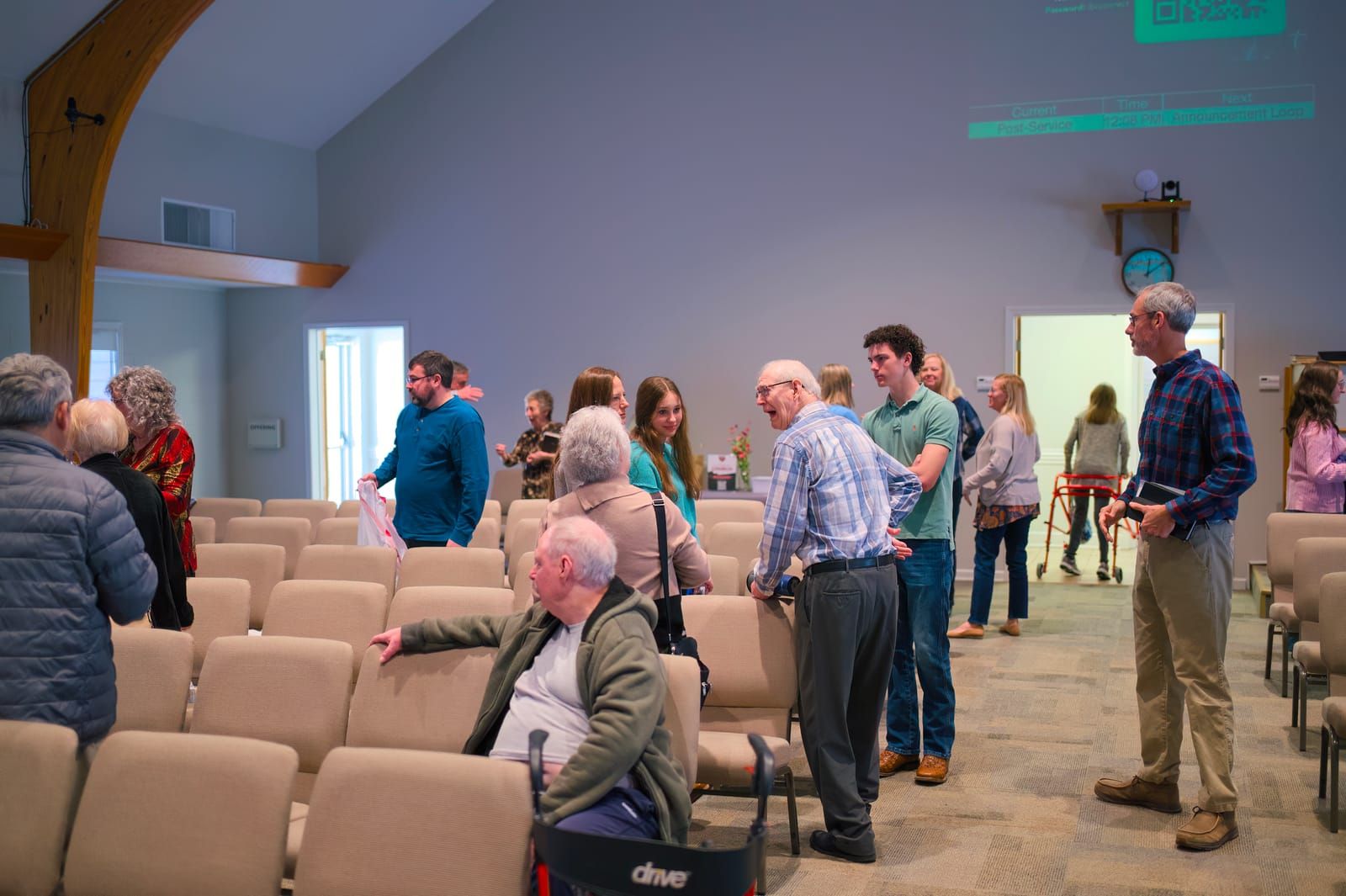 Church members greeting one another among the rows of sanctuary chairs.